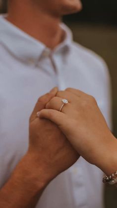 a close up of a person holding the hand of another person wearing a white shirt