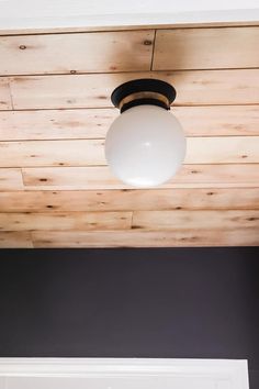 a light fixture hanging from the ceiling in a room with wood paneling and black walls