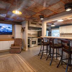 a kitchen with bar stools and a television mounted to the wall in front of it