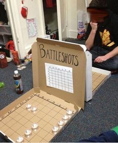 a man sitting on the floor next to a cardboard box with a game in it