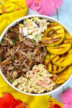 a white bowl filled with meat and macaroni salad next to some pink flowers