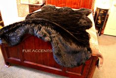 the fur is laying on top of the wooden bed headboard and foot board in this bedroom