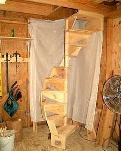 a spiral staircase made out of wooden planks in a room with unfinished walls and wood flooring