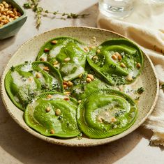 a bowl filled with green peppers covered in pesto and pine nuts on top of a table