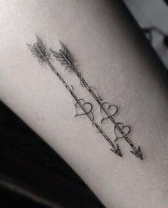 an arrow and heart tattoo on the arm