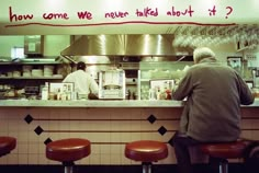 a man sitting at a counter in front of a restaurant with writing on the wall