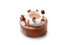 a chocolate dessert with nuts and icing on it's top, sitting on a white surface