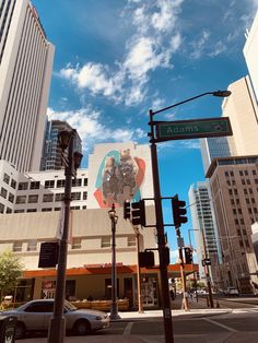 an intersection with traffic lights, street signs and tall buildings in the background on a sunny day