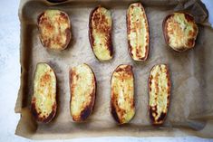 baked potato wedges on parchment paper lined up in a baking pan, ready to go into the oven