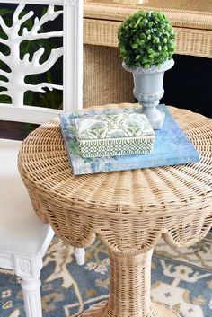 a wicker table topped with a book and a potted plant on top of it