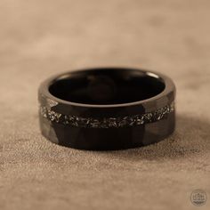 a black wedding band with white diamonds on the inside is shown in close up view