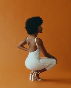 a woman sitting on a stool with her back to the camera and wearing white shoes