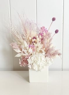 a white vase filled with lots of purple and white flowers