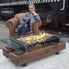 a woman sitting in a chair next to a table with a fire pit on it