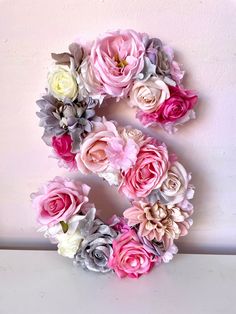 the letter s made out of flowers on a white surface with pink and grey colors