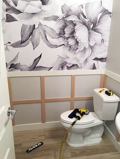 a white toilet sitting in a bathroom next to a wall with flowers painted on it