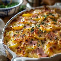 a casserole dish with ham and cheese in it on a wooden table next to other dishes