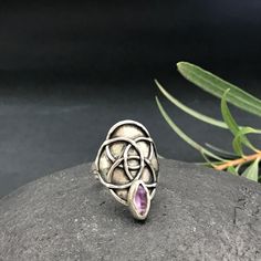 This unique, handcrafted silver ring features an beautiful Amethyst stone set in an organic design inspired by the Flower of Life.  The oxidized and textured finish adds depth and character, while its wrap-around style embraces the finger beautifully.  Adjustable for a perfect fit, this long talisman ring is not just jewelry--it's a powerful statement piece that carries meaning and elegance.  Perfect for those who appreciate one-of-a-kind creations. This piece is entirely handcrafted by me, using traditional jewelry techniques to solder sterling silver (925). Each piece is unique! Adjustable: 7,5 to 10 Us size Top ring size: 1,18" 30mm Amethyst: 0,19" x 0,39" 5 x 10 mm Band width: 0,15" 4mm Don't know your ring size? Go here: http://www.onlineconversion.com/ring_size.htm Your jewelry will Handmade Bohemian Amethyst Ring, Bohemian Sterling Silver Amethyst Ring, Luxury Handmade Sterling Silver Amethyst Ring, Luxury Handmade Spiritual Amethyst Ring, Spiritual Amethyst Cabochon Ring For Gift, Talisman Jewelry, Unusual Rings, Top Rings, Organic Design