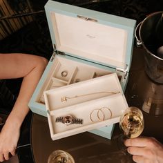 two people are holding wine glasses with jewelry in their hands and one is sitting on the table