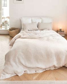 a bed with white sheets and pillows on top of it in a room next to a window