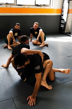 four men sitting on the ground in a circle while one man holds his leg up