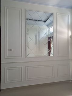 an empty room with white walls and large mirror