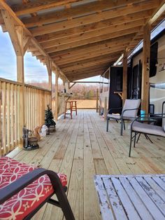 a wooden deck with chairs and tables on it's side, next to an awning