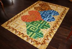 a multicolored area rug on the floor in a room with wooden floors and chairs