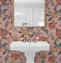 a white sink sitting under a mirror next to a wall mounted faucet in a bathroom