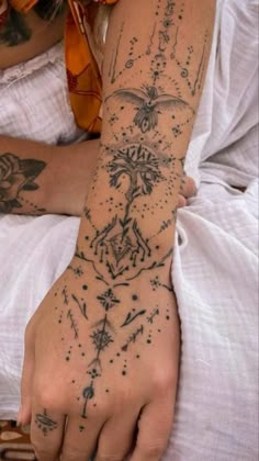 a woman's arm with tattoos on it and her hand in the air,