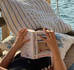 a woman is reading a book on the beach