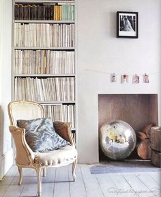 a chair sitting in front of a fire place next to a book shelf filled with books