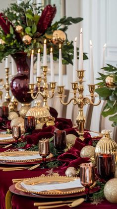 the table is set with red and gold plates, silverware, and candlesticks