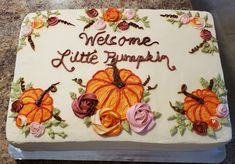 there is a cake decorated with flowers and pumpkins on the counter top that says welcome little pumpkin