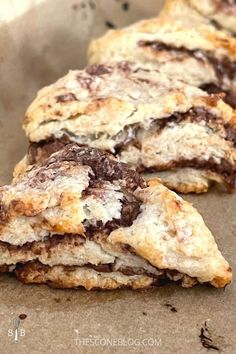 two chocolate filled scones sitting on top of a piece of parchment paper next to each other