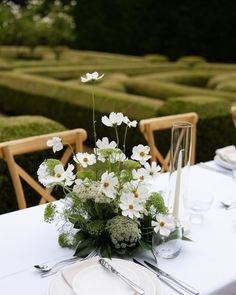 a table with white flowers and greenery in the center is surrounded by mazes