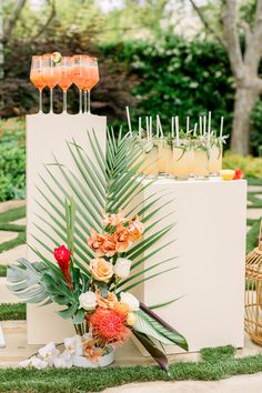 an arrangement of flowers and drinks on display in the grass at a backyard wedding reception