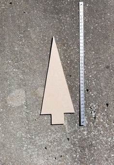 a wooden christmas tree sitting next to a ruler on the ground with holes in it