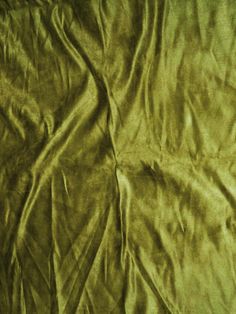 a bed covered in a green blanket next to a pillow