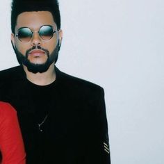 two people standing next to each other in front of a white wall and wearing sunglasses