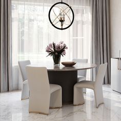 a dining room table with white chairs and a chandelier hanging from the ceiling