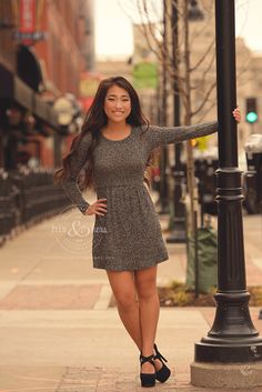 a woman standing next to a lamp post on a sidewalk with her arms out in the air