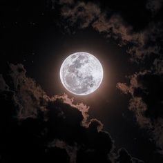 the full moon is shining brightly in the dark night sky with fluffy clouds around it