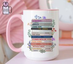 a pink and white coffee mug sitting on top of a table next to a clock