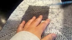 a hand is touching the surface of a knitted blanket on top of a table