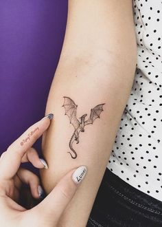 a woman's arm with a small dragon tattoo on the left side of her arm