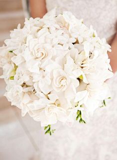 a bride holding a bouquet of white flowers