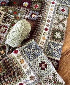 a crocheted afghan and ball of yarn sitting on a wooden floor next to each other