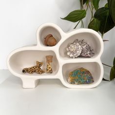 a white shelf with three compartments filled with different types of rocks and animal figurines