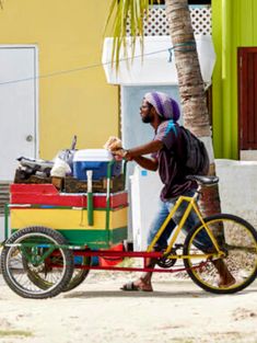 a man riding a bike with a cart attached to it's front wheel and carrying items on the back